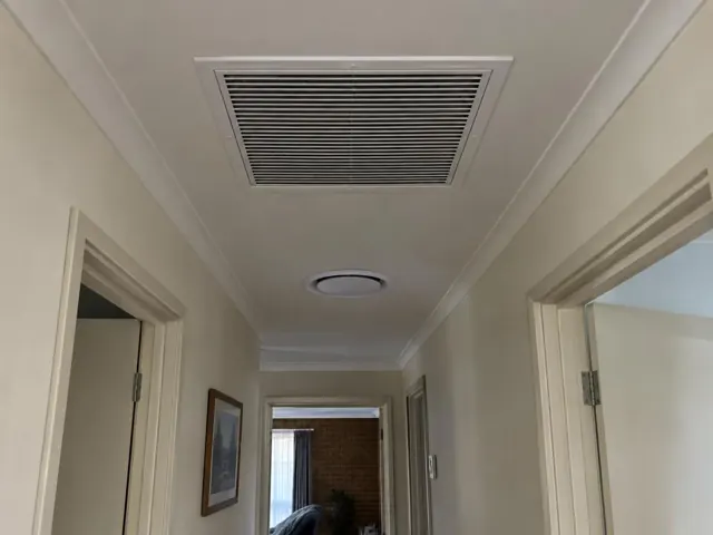 Ceiling return-air grille in a narrow hallway with doors and beige walls in Modbury Heights